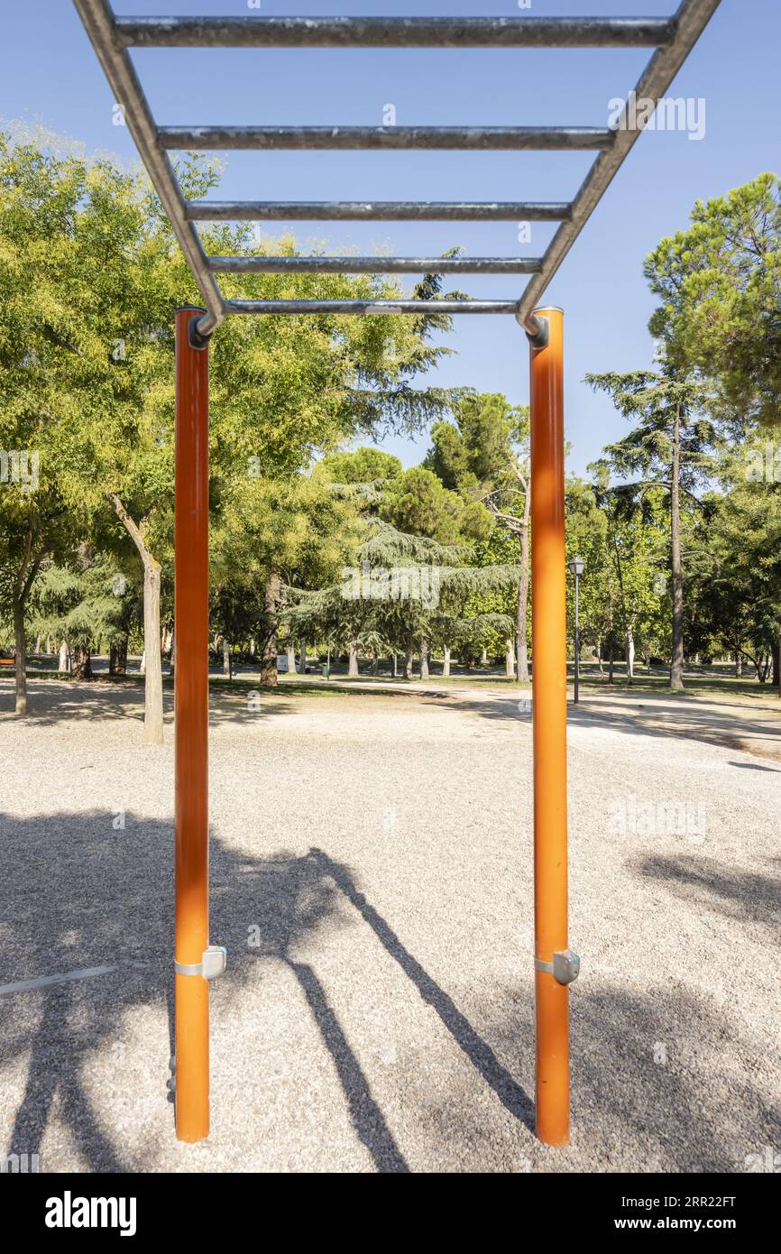 Fitnessgeräte für Sportarten in einem Park mit Schotteroberfläche und vielen Laubbäumen Stockfoto