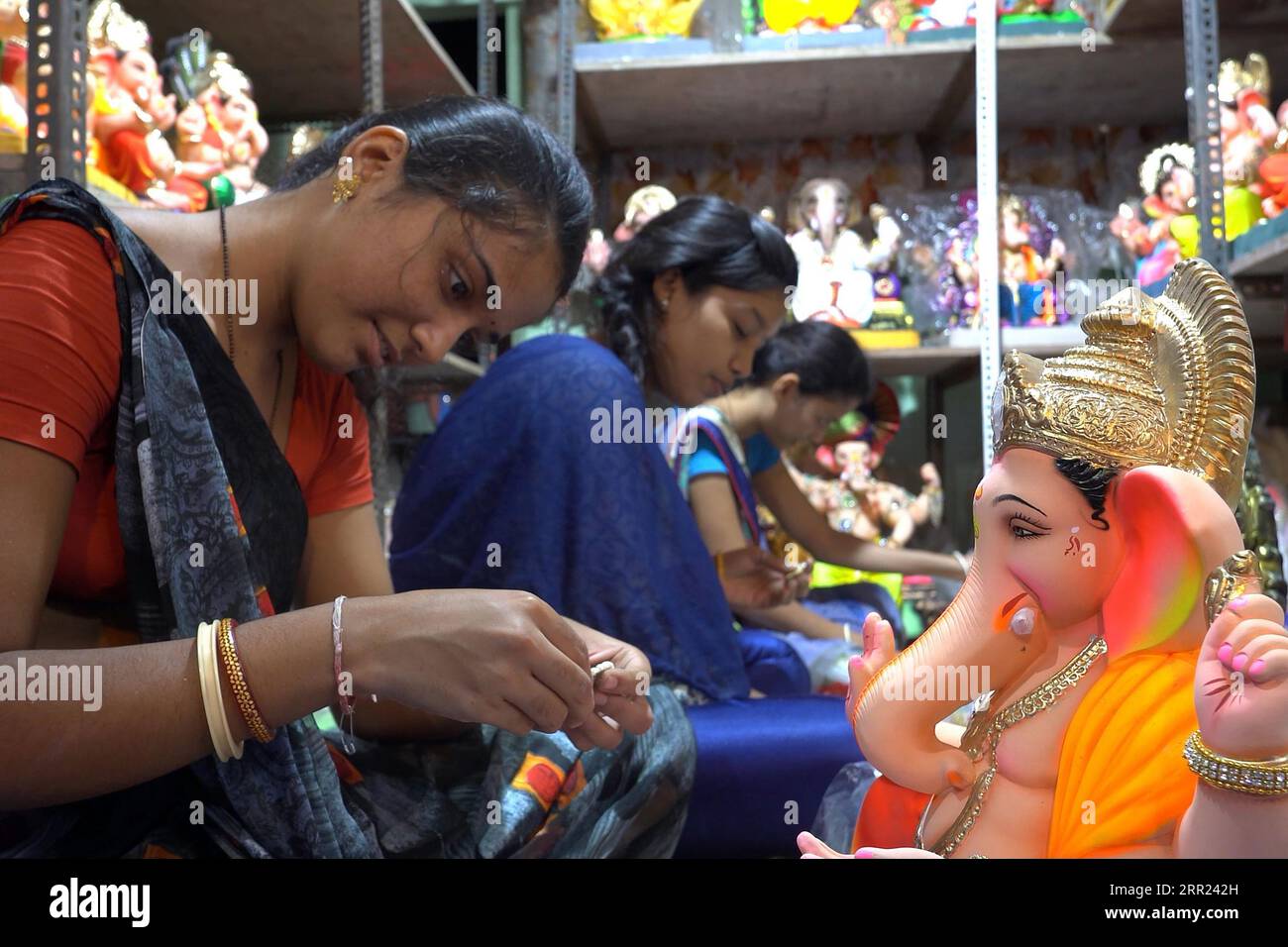 Frauen malen Ganesh-Statuen in einer kleinen Werkstatt auf dem Lalbaug-Markt in Mumbai, Indien Stockfoto