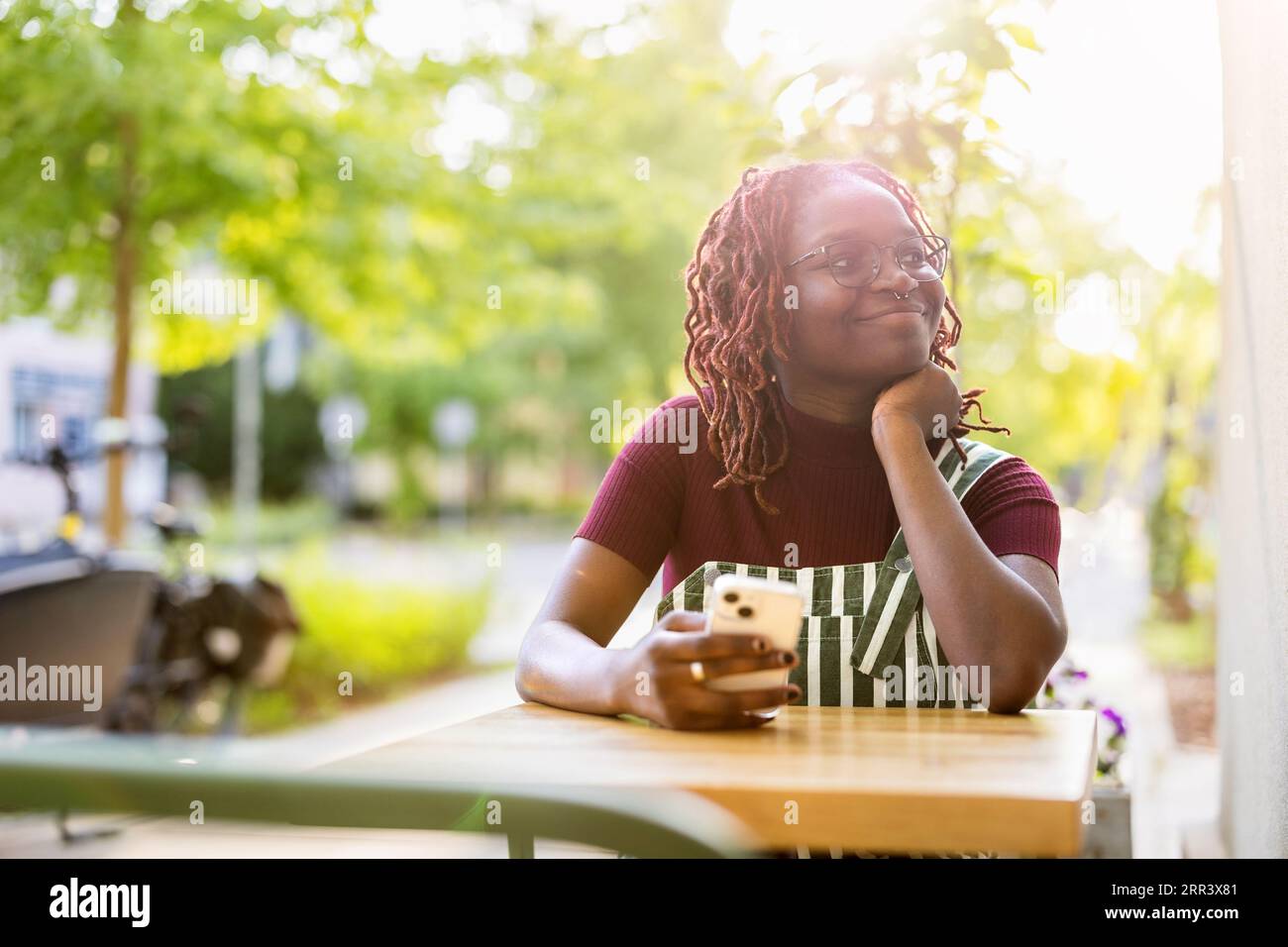 Porträt einer schwarzen nichtbinären Person, die in einem Café im Freien sitzt Stockfoto