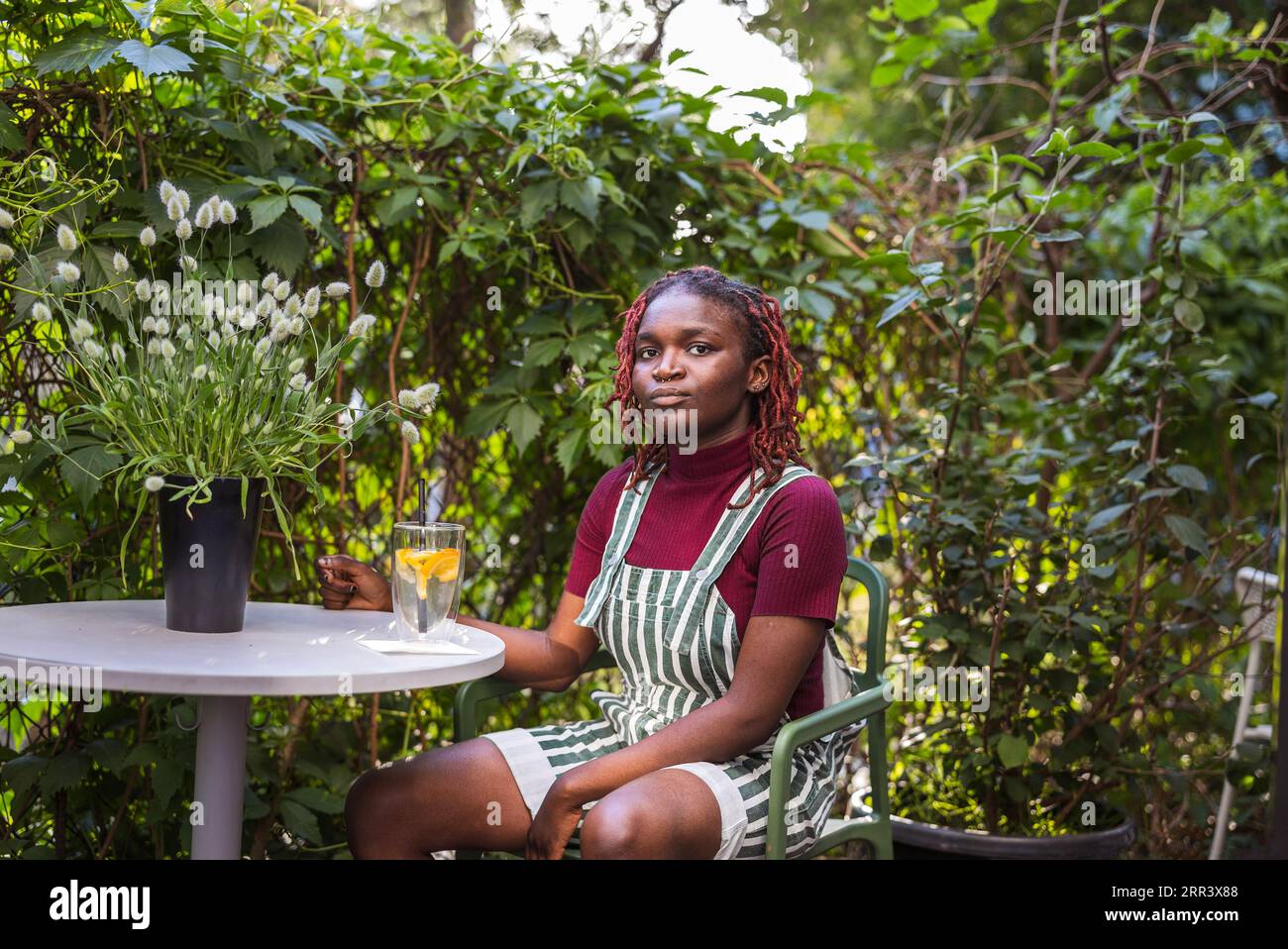 Porträt einer schwarzen nichtbinären Person, die in einem Café im Freien sitzt Stockfoto