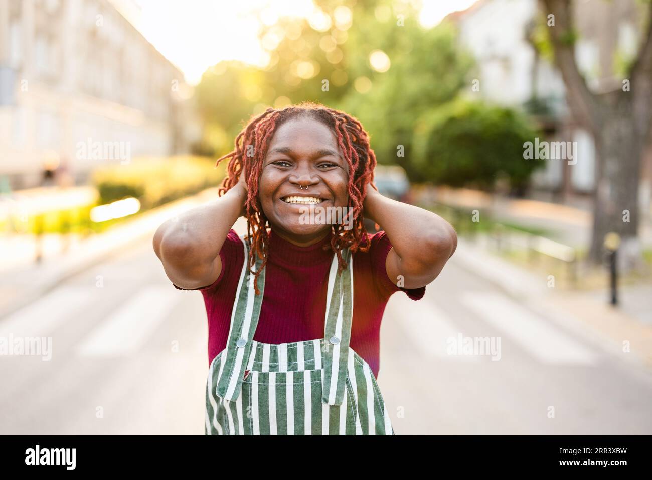 Fröhliche, nicht-binäre Person, die auf der Straße in der Stadt steht Stockfoto