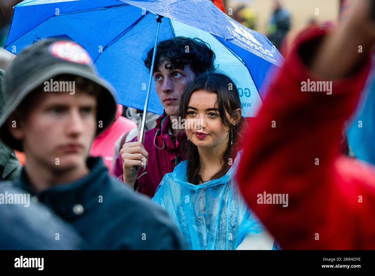 Ein junges Paar versteckt sich unter einem Regenschirm im Regen und Schlamm. Green man Festival, Brecon, Wales, Großbritannien, 2023. Foto: Rob Watkins Stockfoto