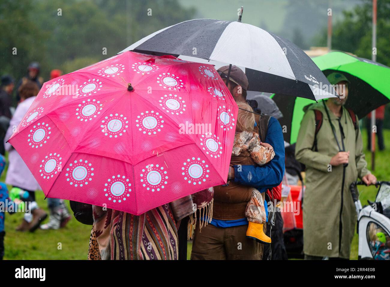 Eine Familie unterbringt Regenschirme bei Regen und Schlamm. Green man Festival, Brecon, Wales, Großbritannien, 2023. Foto: Rob Watkins Stockfoto