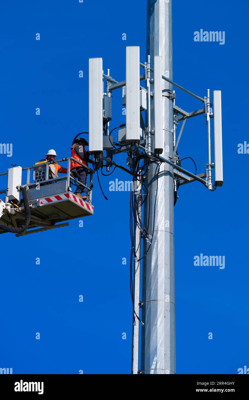 Der Techniker und Arbeiter des Mobilfunkturms führt Reparaturen an einem Mobilfunkturm in Victoria, Australien, mit blauem Himmel durch. Stockfoto