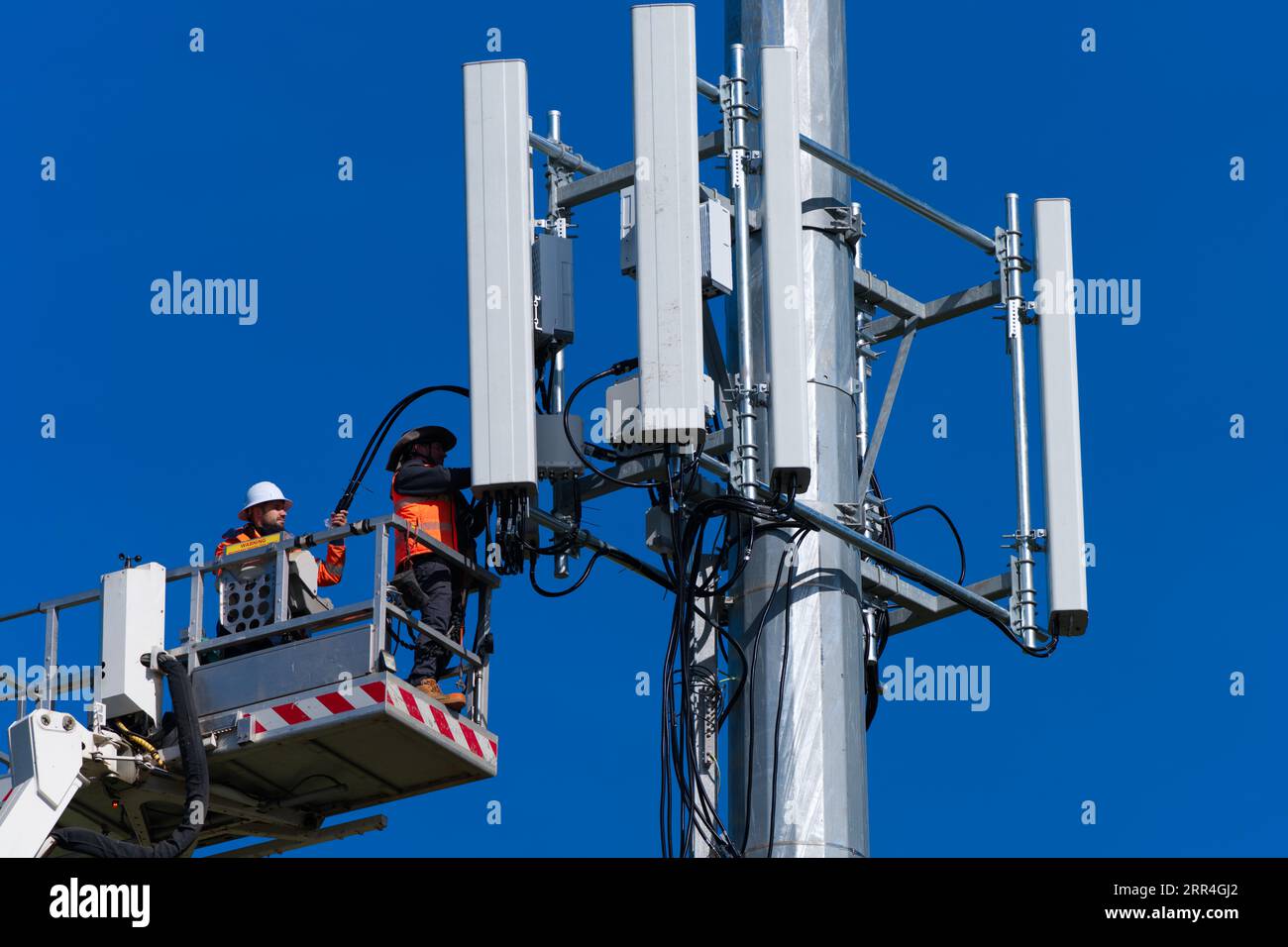 Der Techniker und Arbeiter des Mobilfunkturms führt Reparaturen an einem Mobilfunkturm in Victoria, Australien, mit blauem Himmel durch. Stockfoto