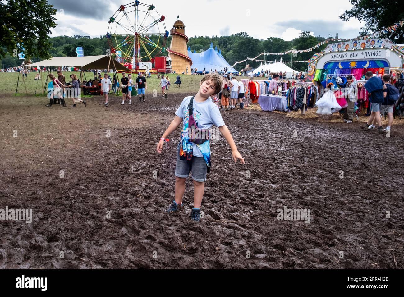 Ein kleiner Junge steckt im Schlamm bei regnerischem Wetter in der Nähe der Imbissstände beim Green man Festival, Brecon, Wales, Großbritannien, 2023 fest. Foto: Rob Watkins Stockfoto