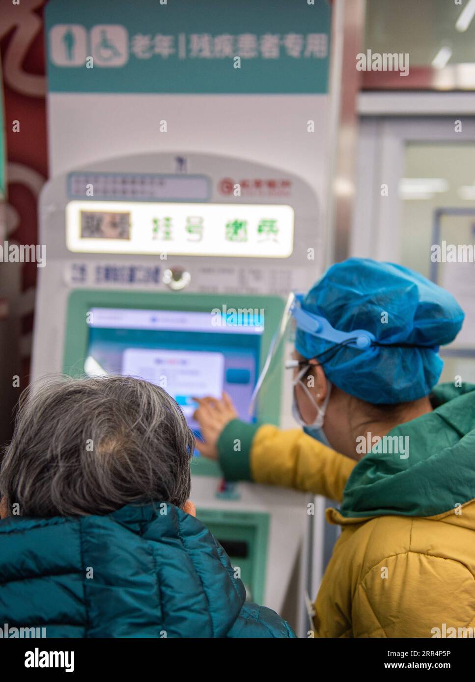 201210 -- PEKING, 10. Dezember 2020 -- Ein Mitarbeiter hilft einem Senioren, den Terminbeleg von einem Gerät für ältere und behinderte Menschen im Xuanwu Krankenhaus der Capital Medical University in Peking, Hauptstadt von China, am 10. Dezember 2020 zu nehmen. China hat eine dreijährige Kampagne gestartet, um den Senioren des Landes dabei zu helfen, die digitale Kluft zu überwinden und die Entwicklung intelligenter Technologien zu genießen. Die Regierung hat vor kurzem einen Plan mit Maßnahmen vorgelegt, die älteren Menschen dabei helfen sollen, Hindernisse für die Nutzung intelligenter Technologien zu überwinden und gleichzeitig die traditionellen Dienste für sie aufrechtzuerhalten. Der Plan ist es Stockfoto