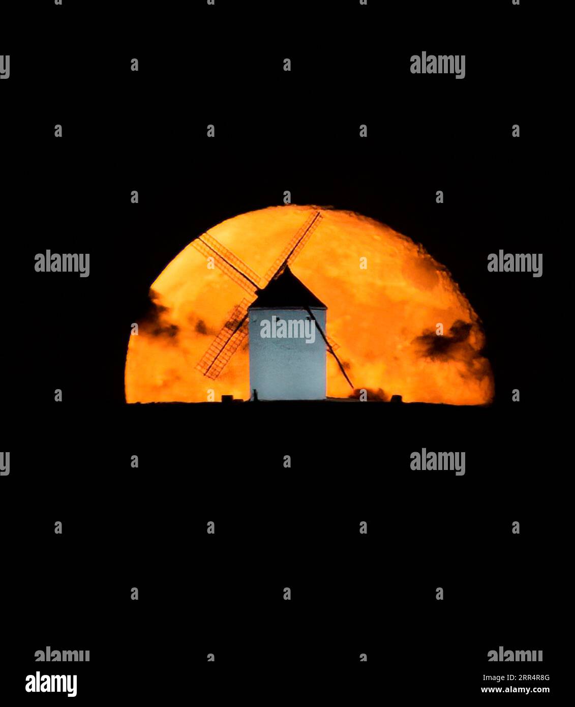 Goldener Supermond mit einigen Wolken, die sich hinter einer Windmühle erheben; auf den Feldern von Castilla, Spanien. Stockfoto