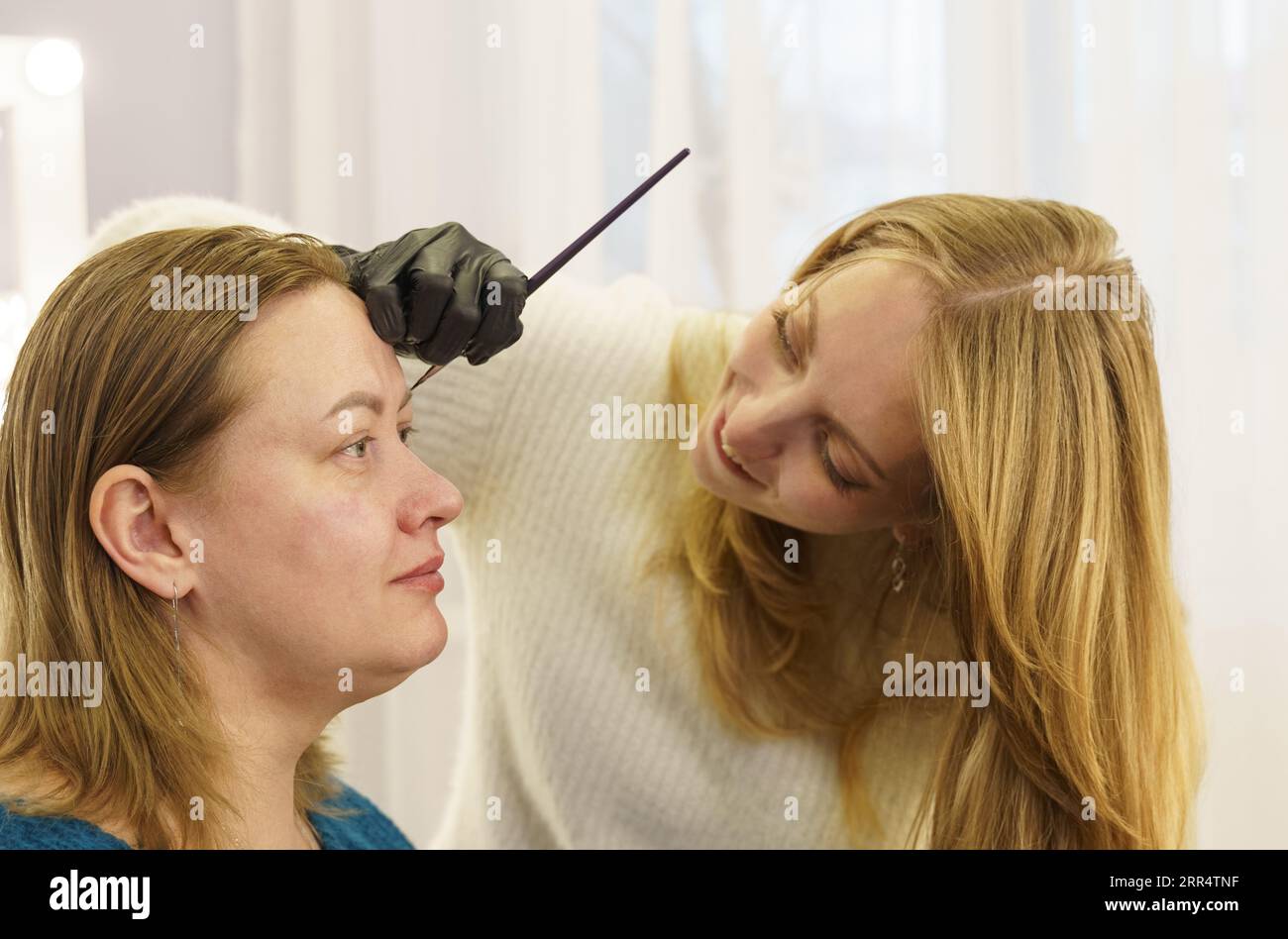 Der Meister zeichnet die Form der Augenbrauen mit weißer Farbe vor der Augenbrauenkorrektur. Schönheitsindustrie. Stockfoto