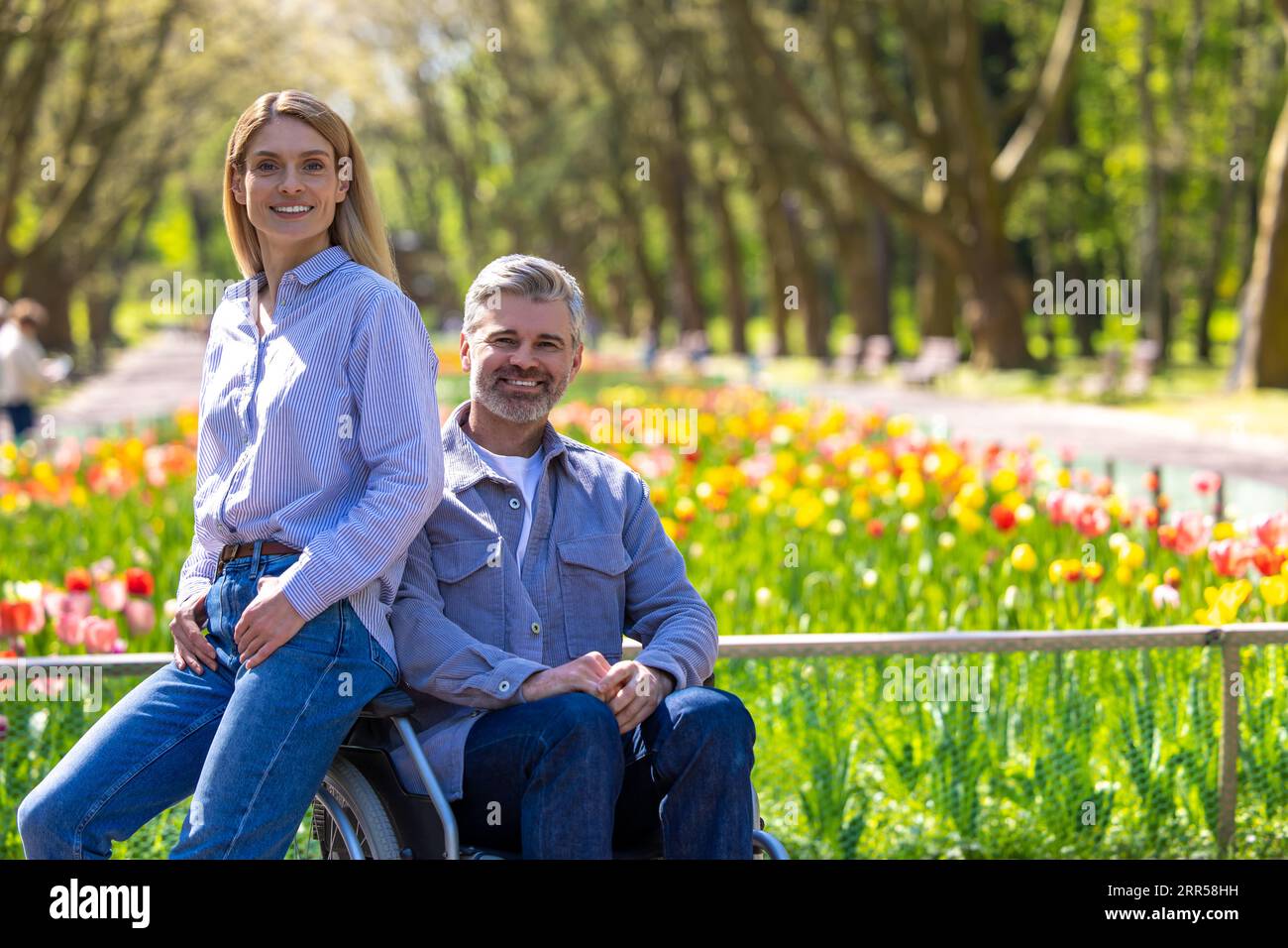 Frau und behinderter Mann im Rollstuhl, die im Park spazieren gehen, romantisches Wandern. Stockfoto