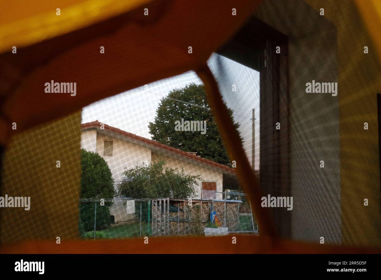 Blick auf Haus und Landschaft durch das Netz eines Imkerhutes und Schleiers. Stockfoto