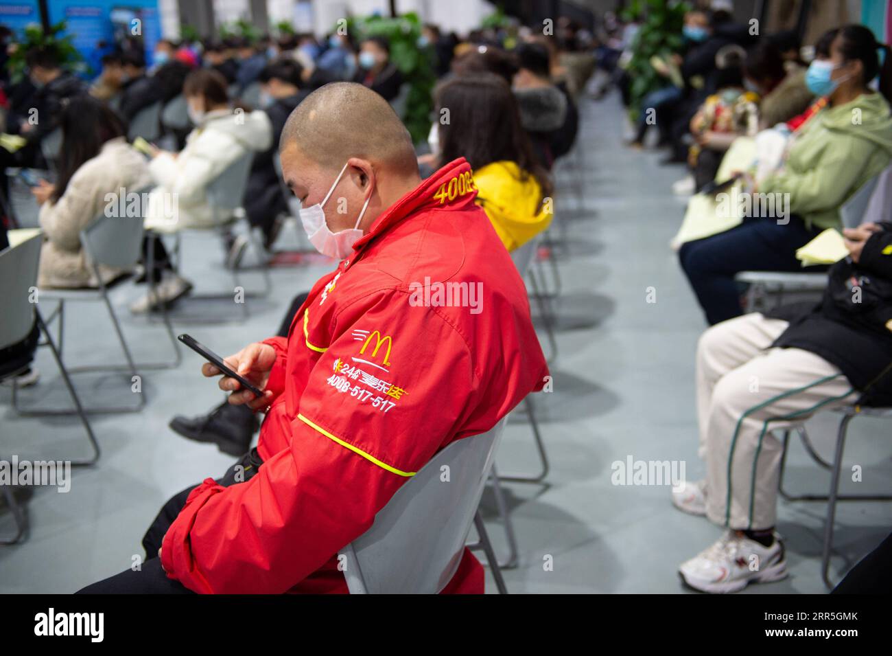 210107 -- PEKING, 7. Januar 2021 -- Eine Lieferperson von McDonald s, die gerade einen COVID-19-Impfstoffschuss erhalten hat, benutzt sein Telefon während seines 30-minütigen Aufenthalts im Beobachtungsgebiet an einer Impfstelle im Bezirk Chaoyang, Peking, Hauptstadt von China, 5. Januar 2021. Ab Januar 2021 wurde in Peking eine stadtweite Impfkampagne gegen COVID-19 gestartet, wo allein im Bezirk Chaoyang etwa 200.000 Menschen in neun spezifischen Gruppen mit höherem Infektionsrisiko an 43 Standorten die Impfstoffe erhielten. XINHUA FOTOS DES TAGES ChenxZhonghao PUBLICATIONxNOTxINxCHN Stockfoto