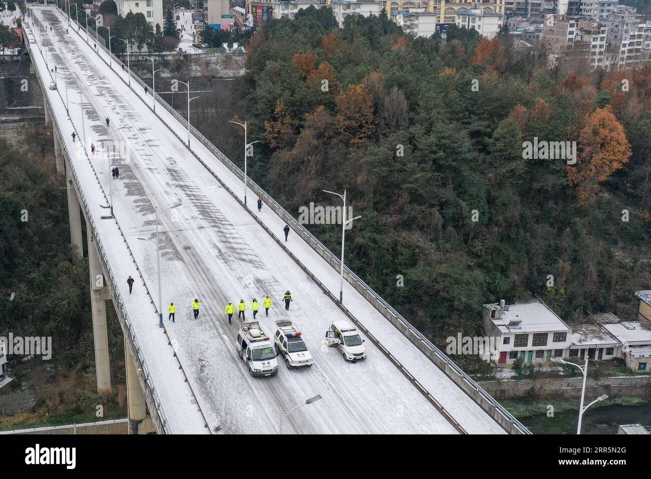 210111 -- PANZHOU, 11. Januar 2021 -- Luftaufnahme am 11. Januar 2021 zeigt Verkehrspolizisten, die auf der Elangpu-Brücke in der Stadt Panzhou in der südwestlichen chinesischen Provinz Guizhou Eis schmelzen. Die jüngste starke kalte Welle hat zu Kongelationen in Panzhou und an vielen anderen Orten in Guizhou geführt. Rund 400 Verkehrspolizisten in Panzhou arbeiten nun rund um die Uhr daran, die Straßenflächen der Stadt zu entfernen. Das fluoreszierende Grün auf ihren Jacken scheint die wärmste Farbe in einem frostigen Winter zu sein. CHINA-GUIZHOU-PANZHOU-POLICE-ICE-MELTING CN OUXDONGQU PUBLICATIONXNOTXINXCHN Stockfoto