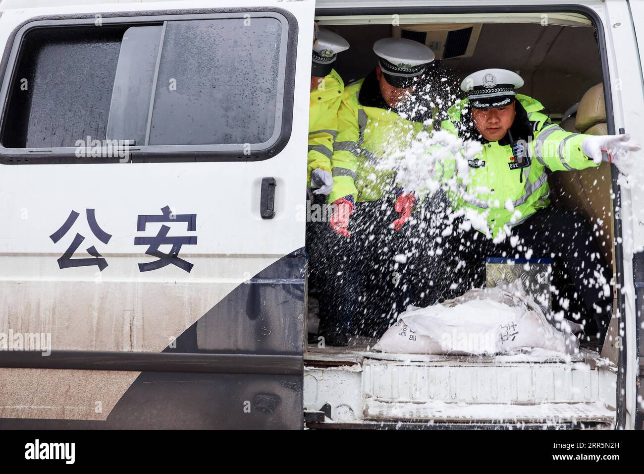 210111 -- PANZHOU, 11. Januar 2021 -- Verkehrspolizisten verbreiten Industriesalz, ein Eisschmelzmittel, auf der Donghu-Brücke in der Stadt Panzhou der Provinz Guizhou im Südwesten Chinas, 11. Januar 2021. Die jüngste starke kalte Welle hat zu Kongelationen in Panzhou und an vielen anderen Orten in Guizhou geführt. Rund 400 Verkehrspolizisten in Panzhou arbeiten nun rund um die Uhr daran, die Straßenflächen der Stadt zu entfernen. Das fluoreszierende Grün auf ihren Jacken scheint die wärmste Farbe in einem frostigen Winter zu sein. CHINA-GUIZHOU-PANZHOU-POLICE-ICE-MELTING CN OUXDONGQU PUBLICATIONXNOTXINXCHN Stockfoto