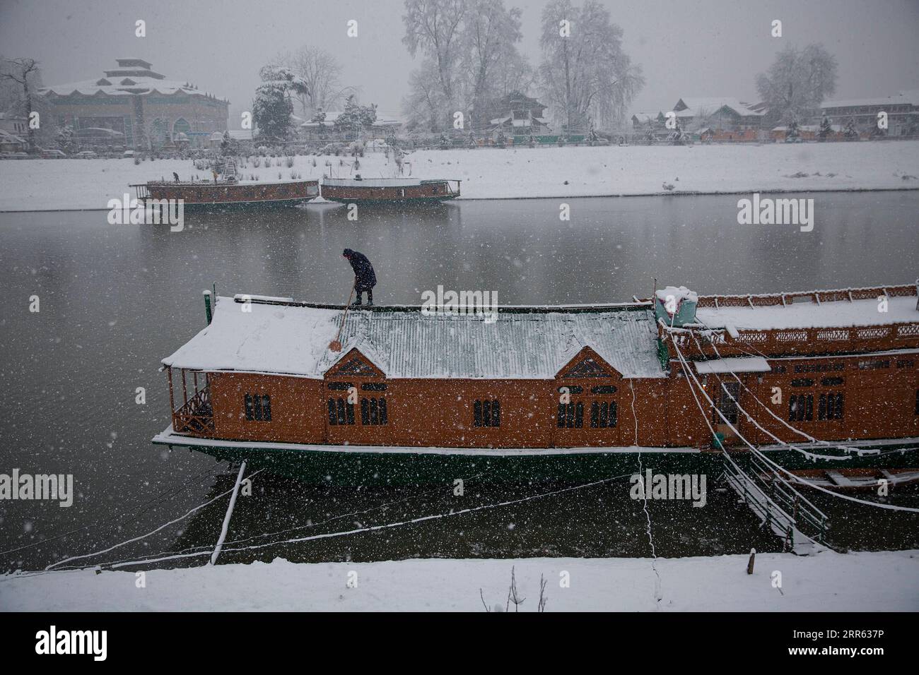 210123 -- SRINAGAR, 23. Januar 2021 -- Ein Mann entfernt Schnee vom Dach eines Hausbootes inmitten von Schneefällen in Srinagar City, der Sommerhauptstadt des von Indien kontrollierten Kaschmirs, 23. Januar 2021. Ein Schneefall traf am Samstag das von Indianern kontrollierte Kaschmir. KASCHMIR-SRINAGAR-SNOWFALL JavedxDar PUBLICATIONxNOTxINxCHN Stockfoto