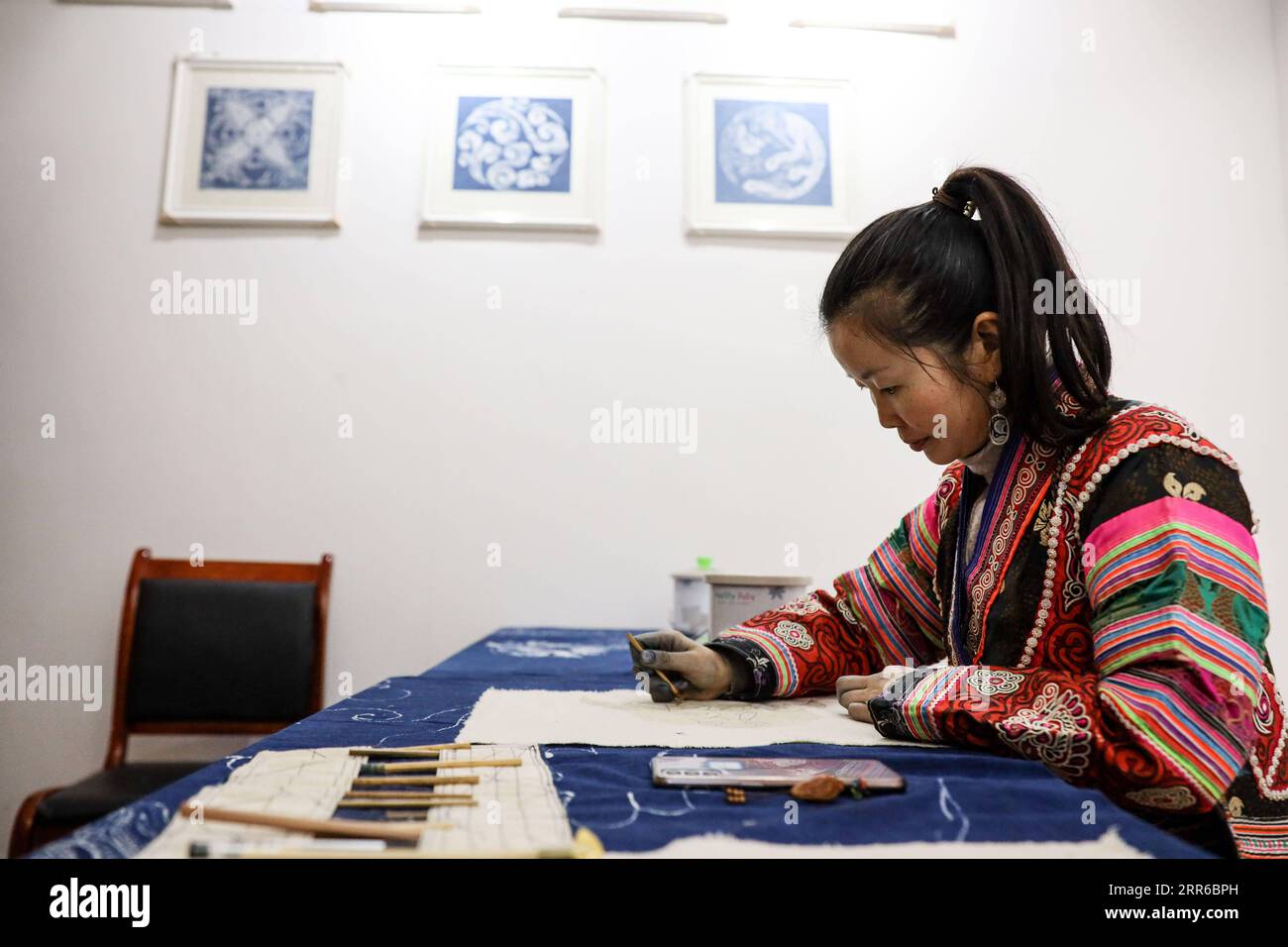 210204 -- QIANXI, 4. Februar 2021 -- Eine Frau aus der ethnischen Gruppe der Miao macht Batik auf einem Workshop zur Armutsbekämpfung im Dorf Huawu, Xinren Miao Township im Qianxi County, Stadt Bijie, Provinz Guizhou im Südwesten Chinas, 3. Februar 2021. Das Dorf Huawu in der Provinz Guizhou im Südwesten Chinas, tief im Wumeng Mountain Area, strotzt vor einer festlichen Atmosphäre, während sich das Frühlingsfest nähert. Mit herrlichen Bergen, breiten Gewässern und malerischer Landschaft wird das Dorf als die Hundert-Meilen-Galerie bezeichnet. In den letzten Jahren hat Huawu Village dank der Politik zur Armutsbekämpfung rasch Fortschritte erzielt Stockfoto