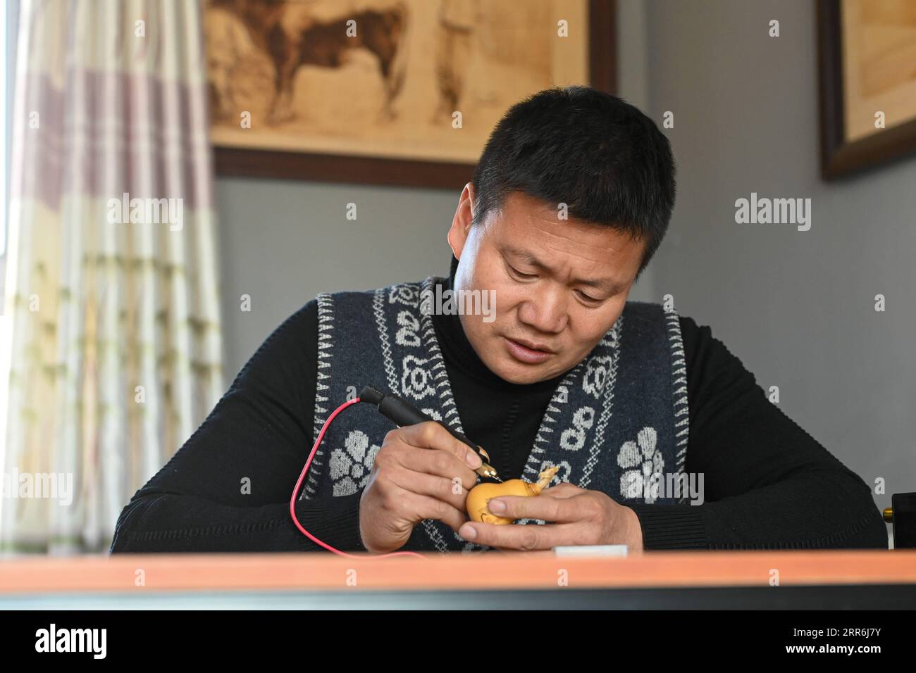 210218 -- HORGOS, 18. Februar 2021 -- Cao Guangyao arbeitet in seinem Atelier in Horgos, Nordwestchinas autonomer Region Xinjiang Uygur, am 6. Februar 2021 an pyrographischen Kalabasarbeiten. Cao Guangyao ist ein 45-jähriger Bauer in Horgos. Er ist auch bei den Einheimischen als Künstler für seine pyrographische Kalabaskunst bekannt. Cao interessierte sich vor 8 Jahren für pyrografische Kreationen aus Fernsehsendungen und begann seitdem mit seiner eigenen Schöpfung. Trotz fehlender Berufsausbildung unternahm Cao immer wieder Kunstversuche mit Liebe und Leidenschaft in der Slacksaison der landwirtschaftlichen Produktion. N Stockfoto