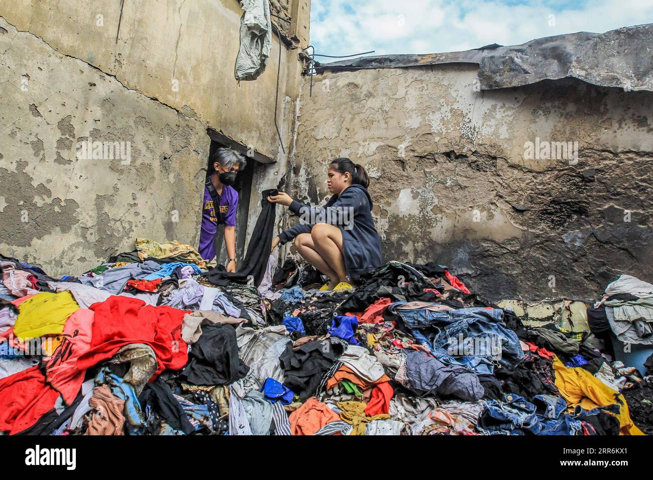 210221 -- MANILA, 21. Februar 2021 -- Bewohner suchen nach intakter Kleidung aus ihrem verkohlten Laden nach einem Brand in einem Slum-Gebiet in Manila, Philippinen, am 21. Februar 2021. Fünf Menschen starben, als ein sechsstündiger Brand rund 300 Häuser im Tondo-Viertel von Manila auf den Philippinen zerstörte, sagte ein Feuerwehrmann am Sonntag. PHILIPPINEN-MANILA-FIRE RouellexUmali PUBLICATIONxNOTxINxCHN Stockfoto