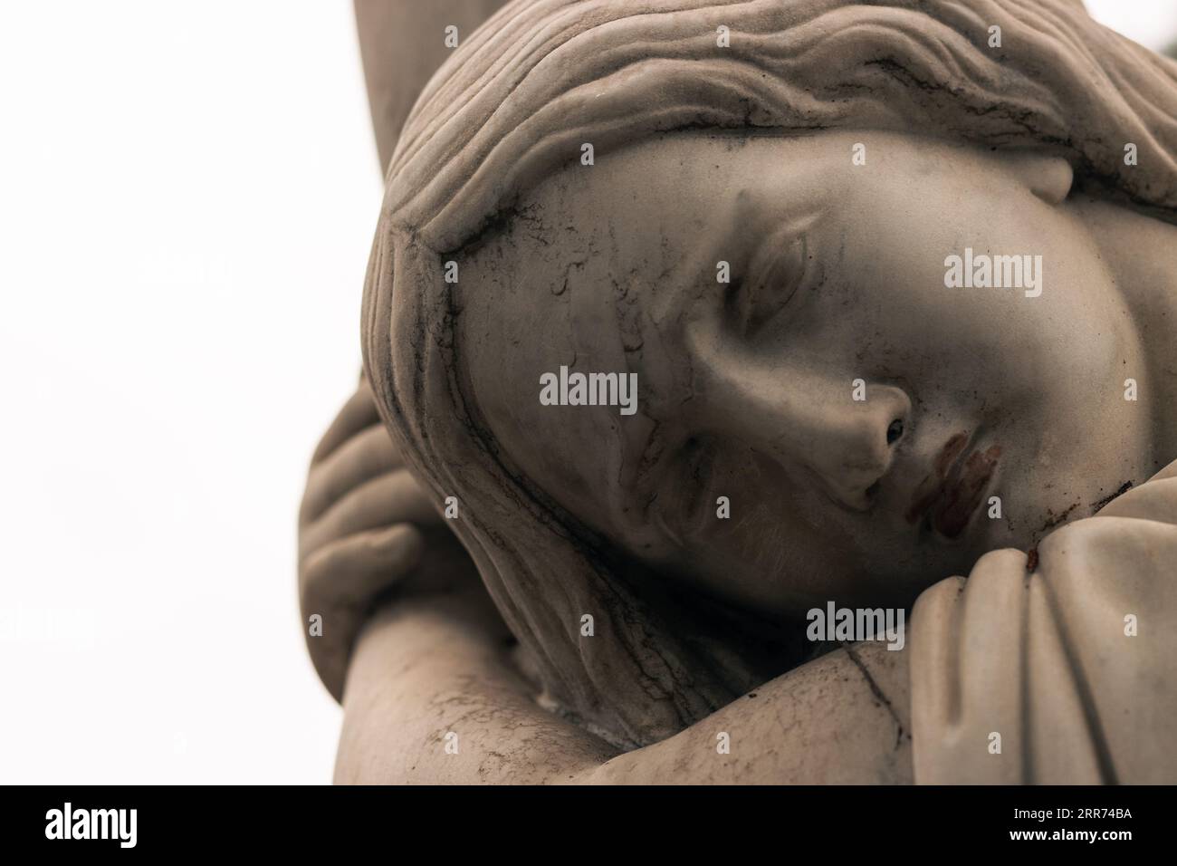 Traurig denkende Frauenstatue mit Blick aus der Nähe in einem Friedhofspark. Stockfoto