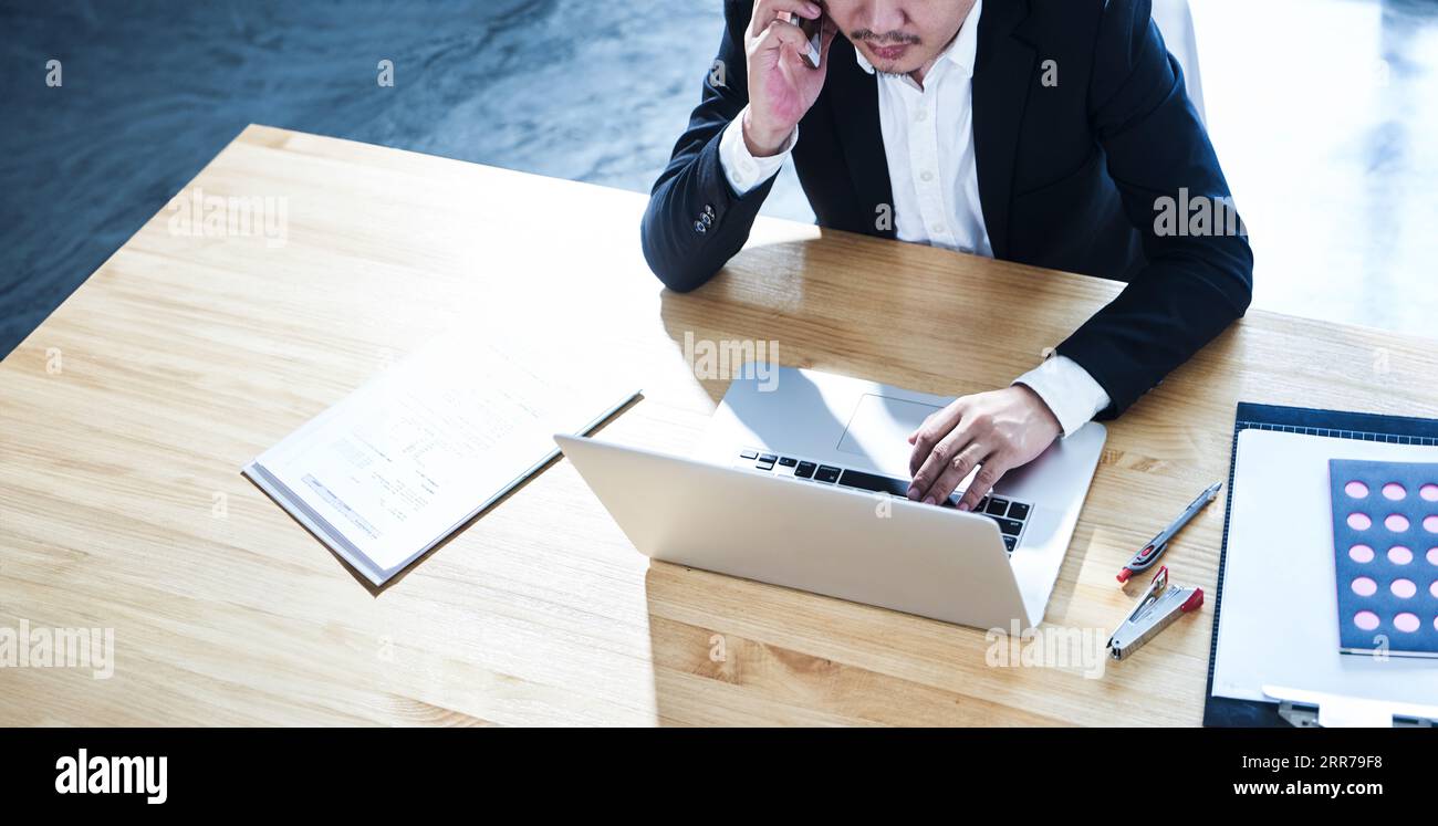 Junge Unternehmer im Büro mit Smartphone und Laptop. Stockfoto
