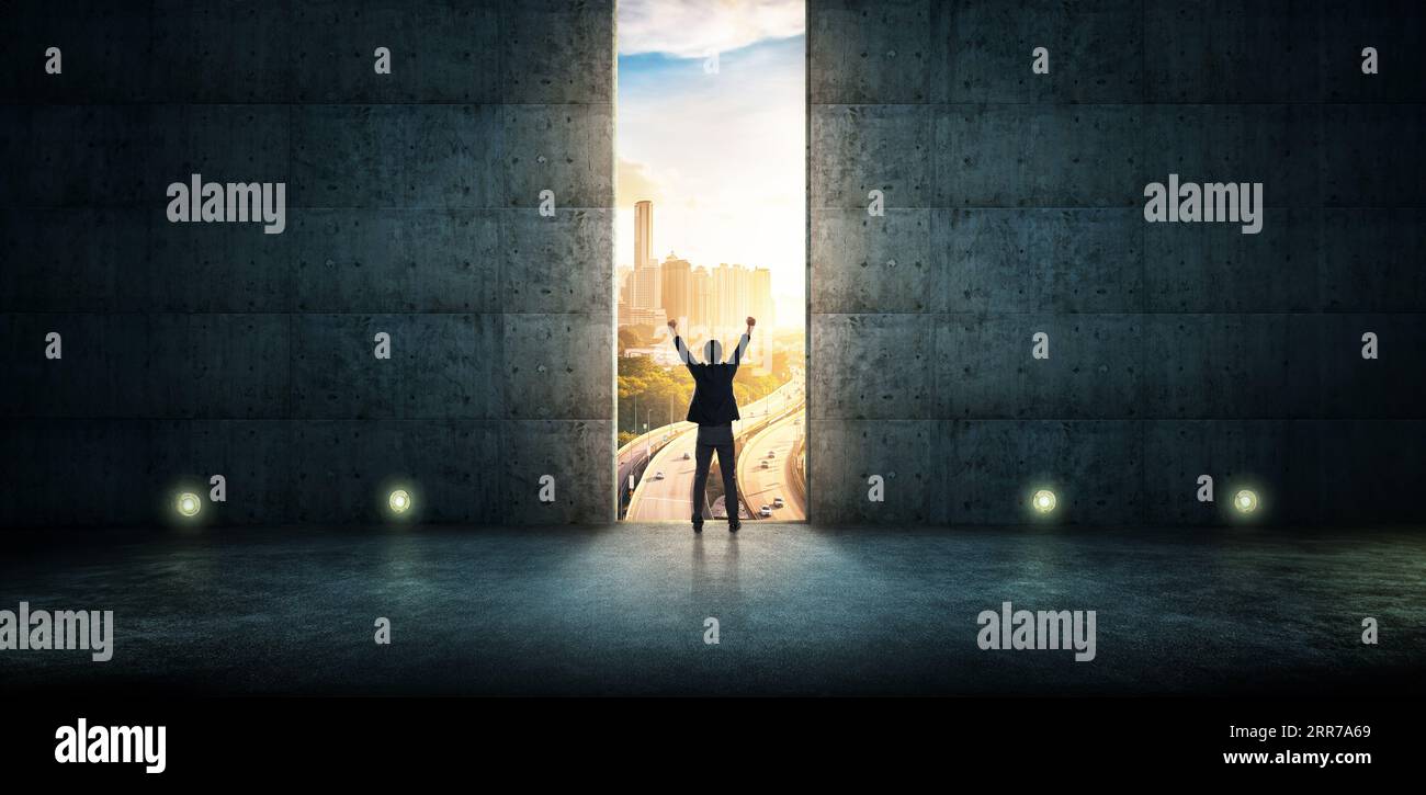 Erfolg Geschäftsmann jubeln gegen Betonwand mit großer Tür, Sonnenaufgang Szene Skyline im freien Blick auf die Stadt. Stockfoto