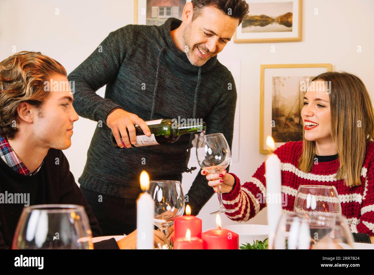 Mann, der ein Glas Wein zum weihnachtsessen füllt Stockfoto