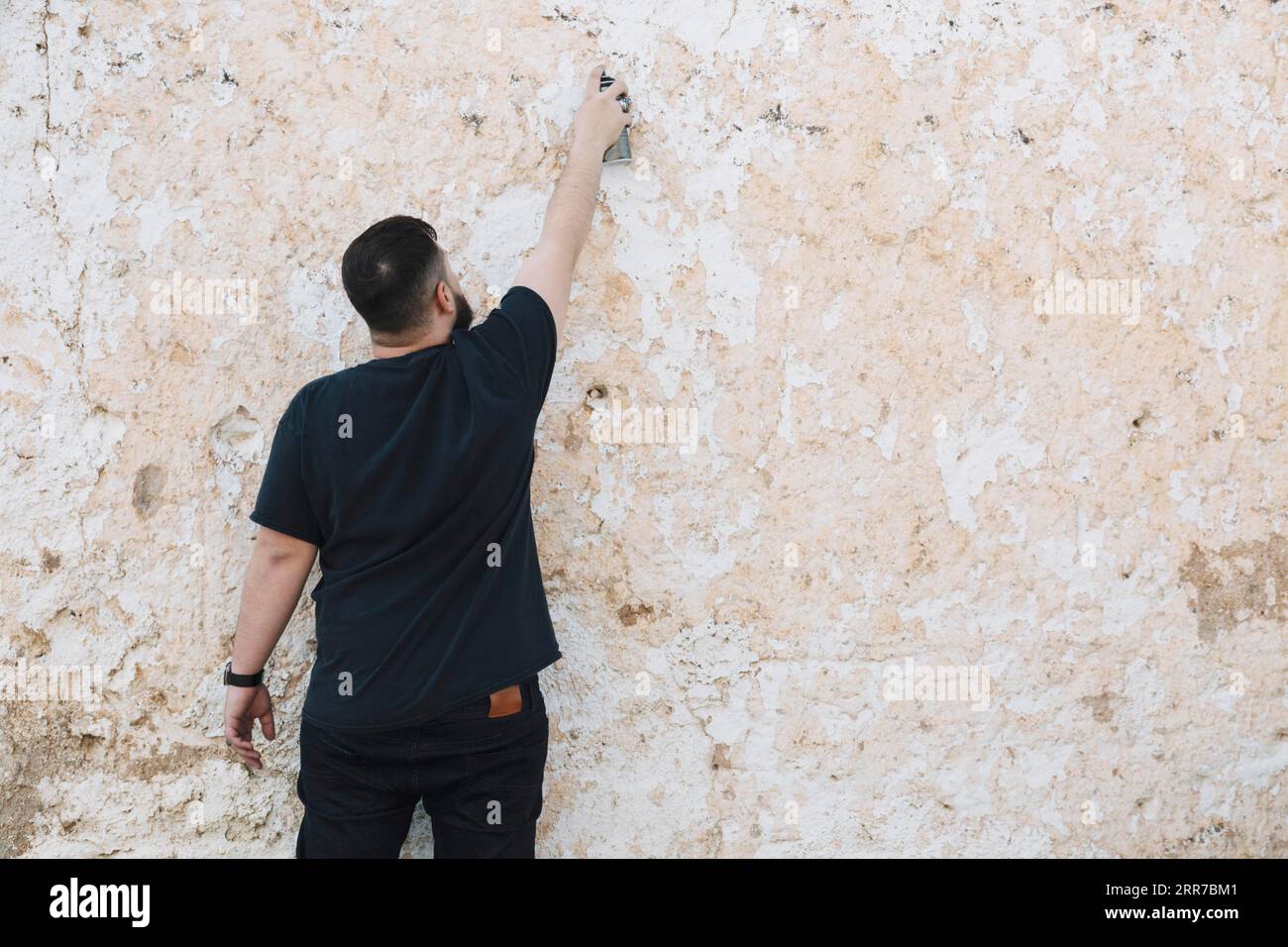 Rückansicht Mann macht Graffiti geschälte Wand Stockfoto