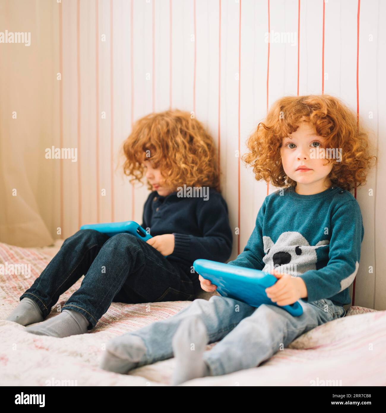 Zwei kleine Mädchen, die mit einem digitalen Tablet im Bett sitzen Stockfoto