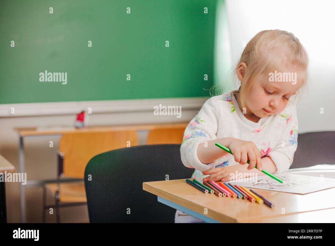 Niedliches Mädchen sitzt Zeichnung Stockfoto