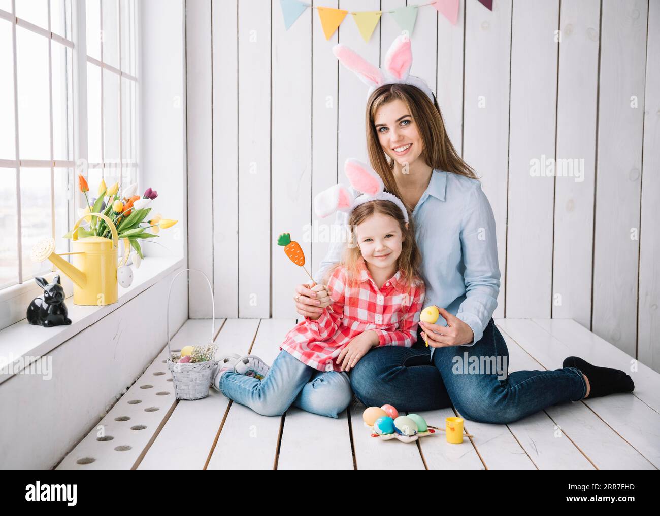 Süße Mädchen Mutter Hasenohren sitzen mit ostereiern Stockfoto