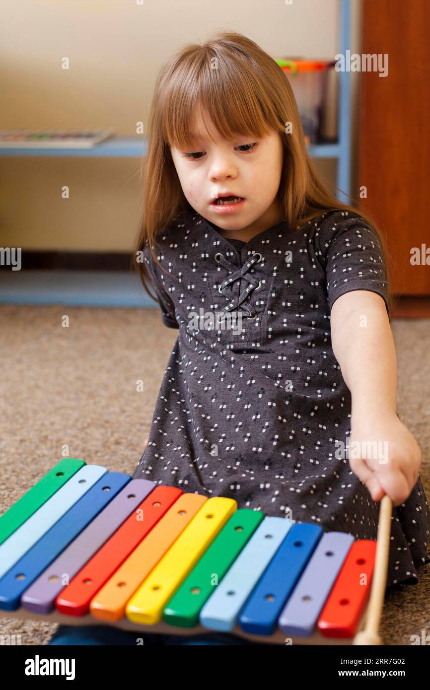 Frontsichtmädchen mit Down-Syndrom, das mit Xylophon spielt Stockfoto