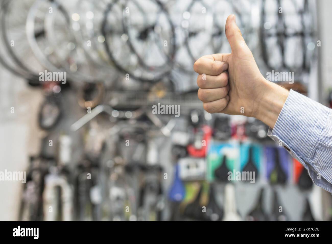 Männlicher Mechaniker, der die Fahrradwerkstatt mit Daumen nach oben bewegt Stockfoto