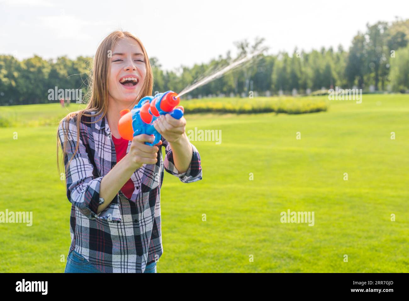 Ein fröhliches Mädchen mit mittlerer Schussweite, das mit einer Wasserpistole spielt Stockfoto