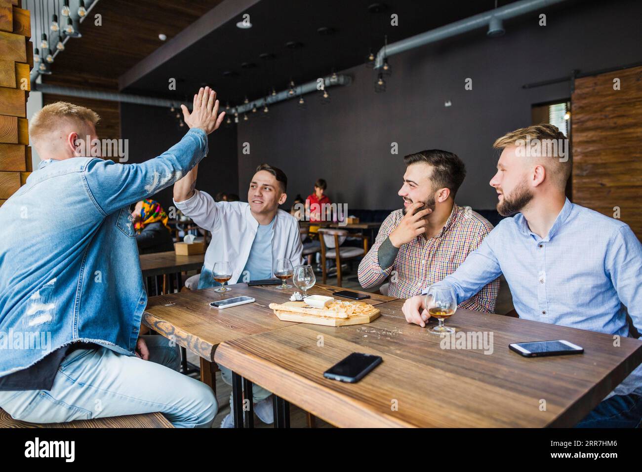 Junger Mann gibt High Five seinen Freunden Restaurant Stockfoto