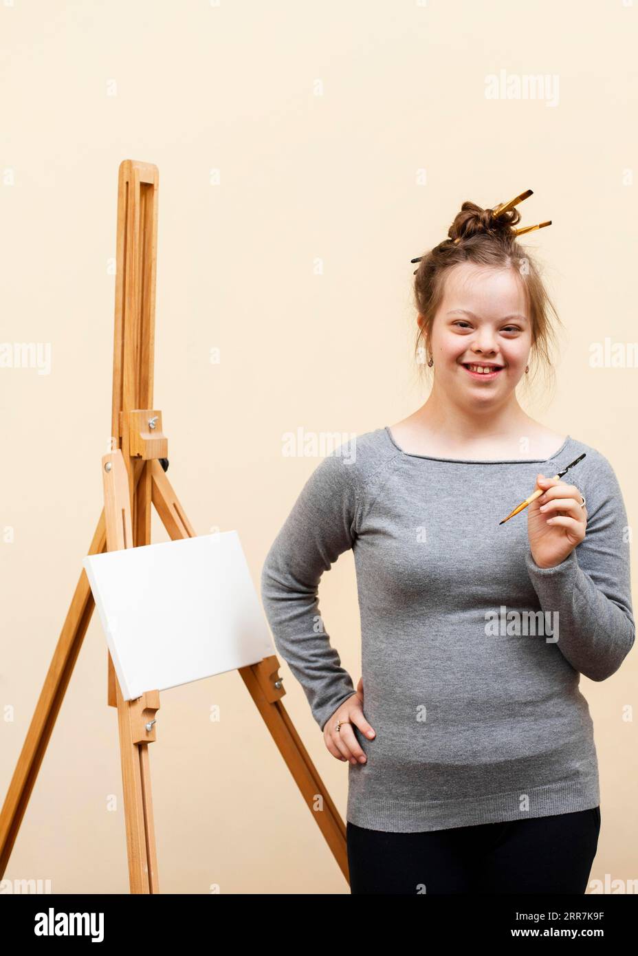 Smiley-Mädchen mit Down-Syndrom, das mit Pinsel posiert Stockfoto