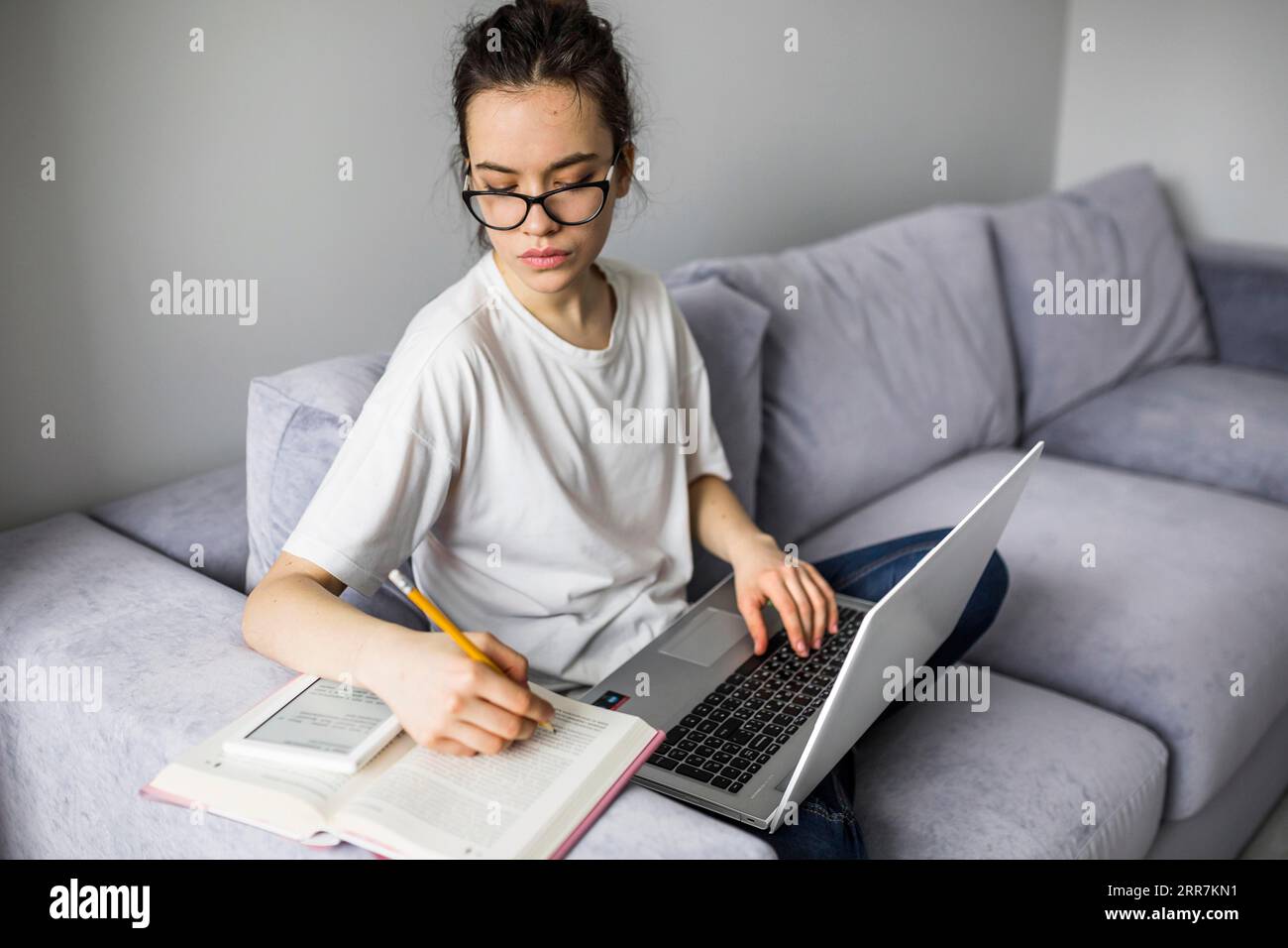 Frau mit Laptop, die ein Notizbuch macht Stockfoto