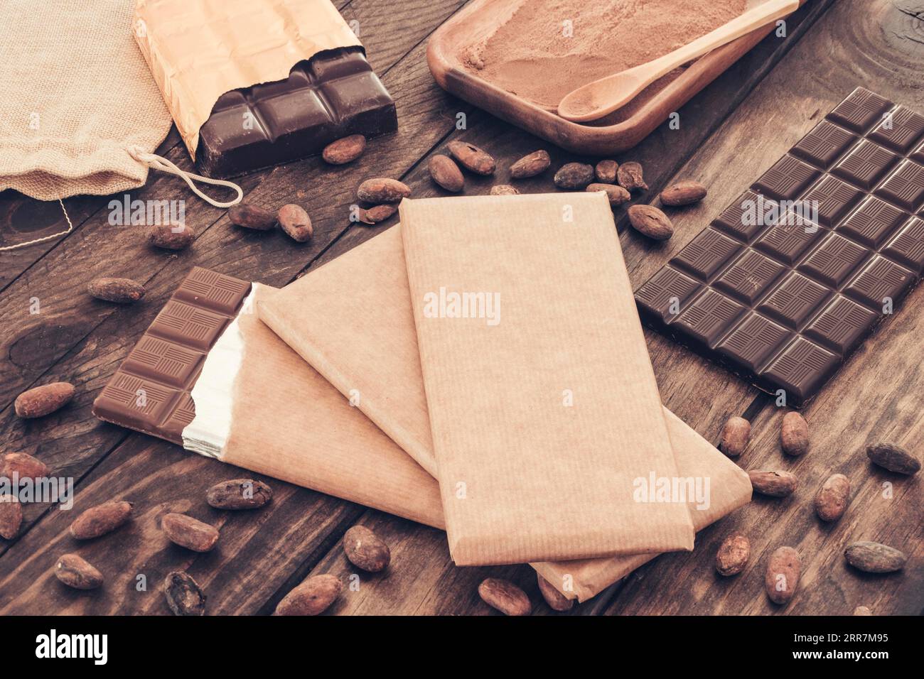 Tafeln aus dunkler Schokolade mit Holztisch aus Kakaobohnen Stockfoto