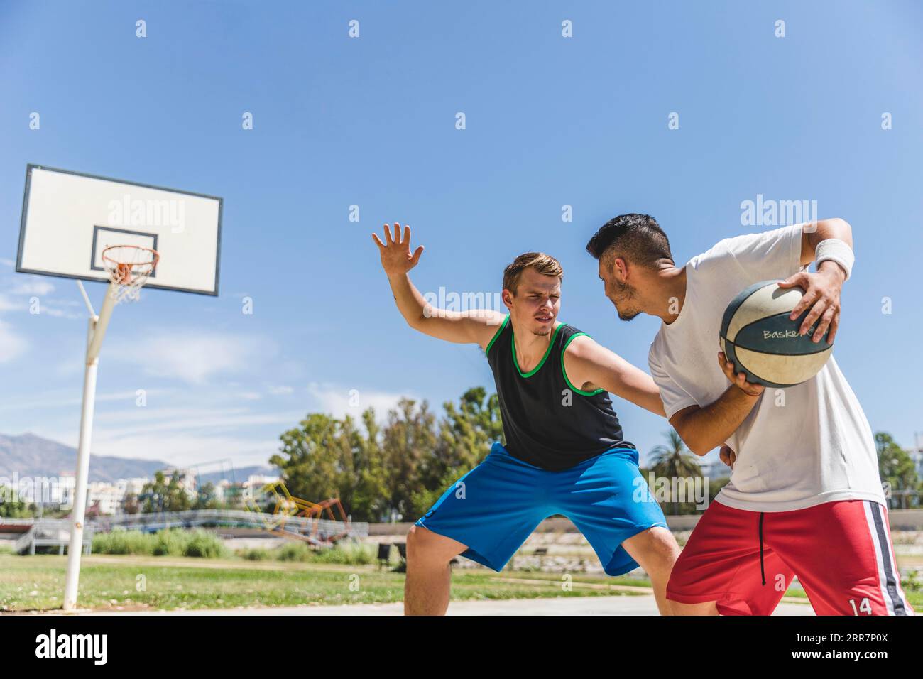 Junger männlicher Spieler spielt mit Basketballspieler Stockfoto