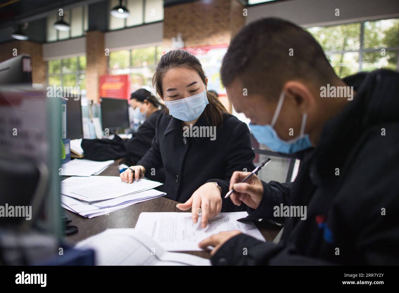 210408 -- WUHAN, 8. April 2021 -- Yuan Fang L, ein Gemeindearbeiter, hilft einem Bewohner beim Ausfüllen eines Formulars in der Qingheju-Gemeinde in Wuhan, Hauptstadt der zentralchinesischen Provinz Hubei, 30. März 2021. Ein Jahr nachdem Wuhan seine 76-tägige Sperrung aufgehoben hatte, um die Verbreitung des neuartigen Coronavirus einzudämmen, hat die Stadt ihr tägliches Leben und ihre wirtschaftlichen Aktivitäten wieder aufgenommen. Während des einjährigen Bestehens leisteten Personen, die an ihren normalen Stellen festhielten, ihren eigenen Beitrag. CHINA-HUBEI-WUHAN-NORMALE MENSCHEN CN XIAOXYIJIU PUBLICATIONXNOTXINXCHN Stockfoto