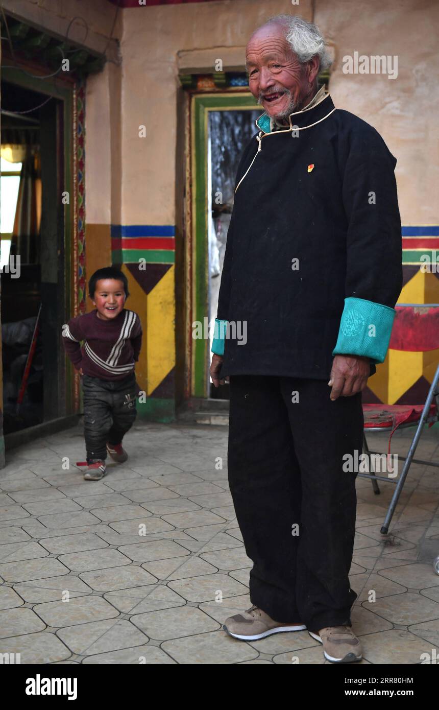 210410 -- LHASA, 10. April 2021 -- Dawa Gokye lächelt, als sein Enkel in ihrer Residenz im Gyadu Village of Jangra Township im Gyangze County of Xigaze City spielt, im Südwesten Chinas autonome Region Tibet, 22. März 2021. Dawa Gokye, 76, einst Leibeigene in einem lokalen Herrenhaus Tibets, hatte bis zur demokratischen Reform 1959 in Hoffnungslosigkeit und Verzweiflung gelebt. In den Augen der Sklavenhalter sind Sklaven nichts anderes als sprechende Werkzeuge, die ihnen ausgeliefert sind. Dawa erinnerte sich, dass sein Kopf vom Verwalter des Herrenhauses schwer verletzt wurde, da der damals 8-Jährige das Wasser nicht heiß genug kochte, um Tee zu machen. Zusammen mit Dutzenden von denen Stockfoto