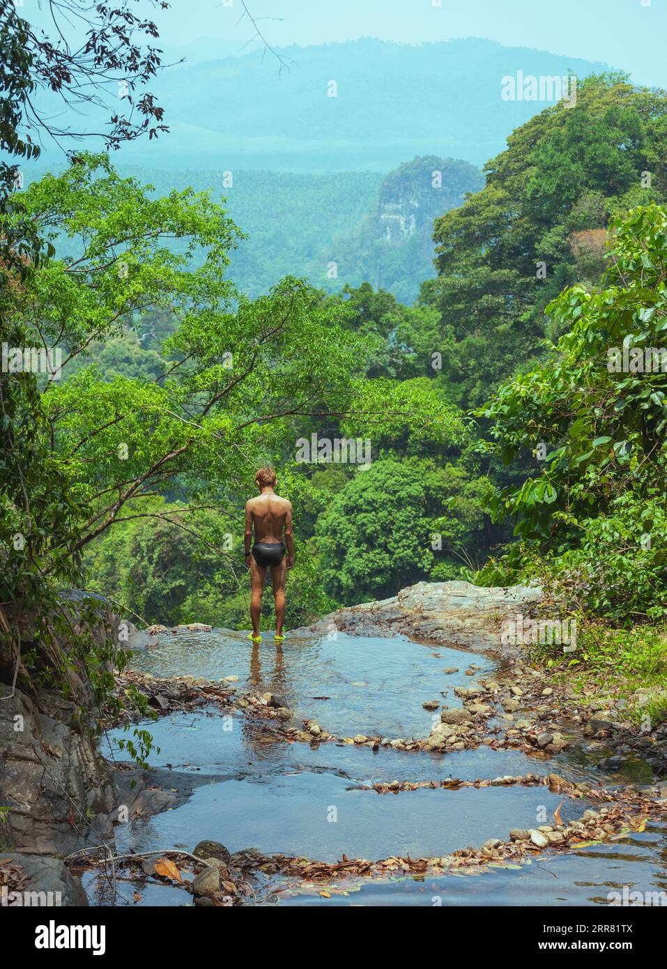 Das Konzept der Einheit mit Natur und Gesundheit. Südostasiatischer (Thai) Mann in Badehose steht am Rande des Wasserfalls im Khao Phanom Bencha Nationalpark Stockfoto