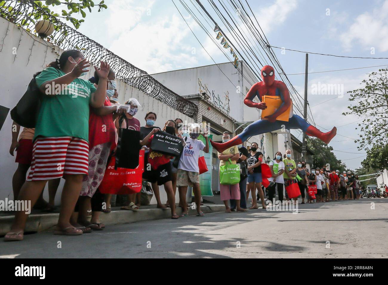 210427 -- MANILA, 27. April 2021 -- Ein Mann, Der als Spider-man verkleidet ist, unterhält Menschen, die sich für kostenlose Waren für ihre Kinder aufstellen, die vom COVID-19-Abriß in Manila, den Philippinen, am 27. April 2021 betroffen sind. PHILIPPINEN-MANILA-COVID-19-SPIDER MAN-FOOD DISTRIBUTION ROUELLEXUMALI PUBLICATIONXNOTXINXCHN Stockfoto