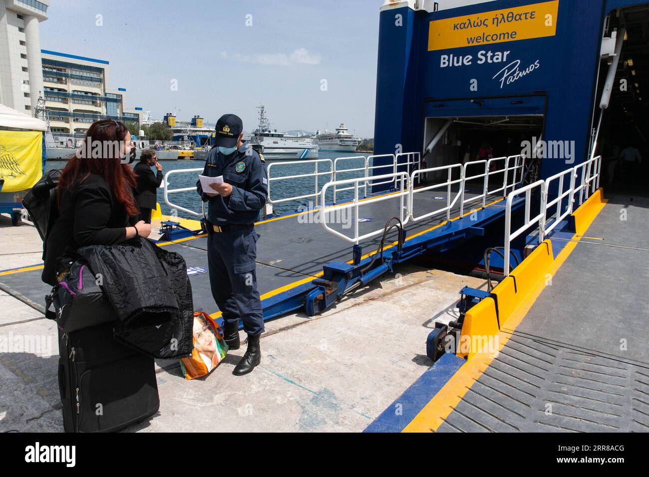 210427 -- PIRÄUS GRIECHENLAND, 27. April 2021 -- Ein Mitglied der griechischen Küstenwache prüft die Reisedokumente eines Passagiers in Piräus, Griechenland, am 27. April 2021. In einer Fernsehansprache vor der Nation letzte Woche sagte der griechische Premierminister Kyriakos Mitsotakis, dass Griechen während des christlich-orthodoxen Osterfestes, das am 2. Mai gefeiert wird, aufgrund der noch immer schweren Seuchenlage nicht frei reisen dürfen. GRIECHENLAND-PIRÄUS-PASSAGIERE-KONTROLLE MariosxLolos PUBLICATIONxNOTxINxCHN Stockfoto