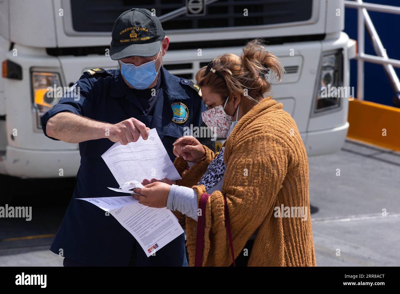 210427 -- PIRÄUS GRIECHENLAND, 27. April 2021 -- Ein Mitglied der griechischen Küstenwache prüft die Reisedokumente eines Passagiers in Piräus, Griechenland, am 27. April 2021. In einer Fernsehansprache vor der Nation letzte Woche sagte der griechische Premierminister Kyriakos Mitsotakis, dass Griechen während des christlich-orthodoxen Osterfestes, das am 2. Mai gefeiert wird, aufgrund der noch immer schweren Seuchenlage nicht frei reisen dürfen. GRIECHENLAND-PIRÄUS-PASSAGIERE-KONTROLLE MariosxLolos PUBLICATIONxNOTxINxCHN Stockfoto
