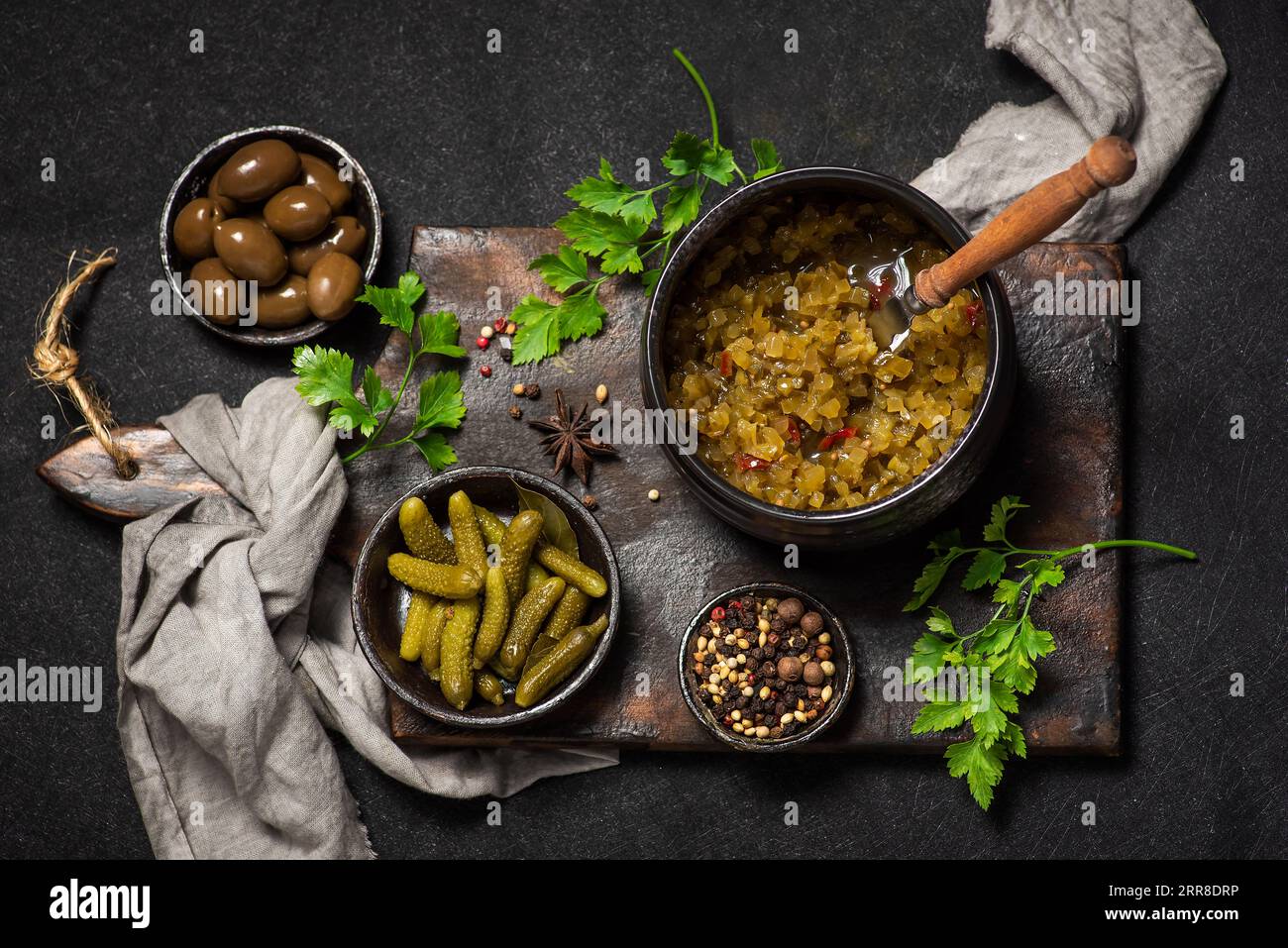 Erfrischender Wintersalat mit eingelegten Gurken und Oliven auf dunklem Holzgrund Stockfoto
