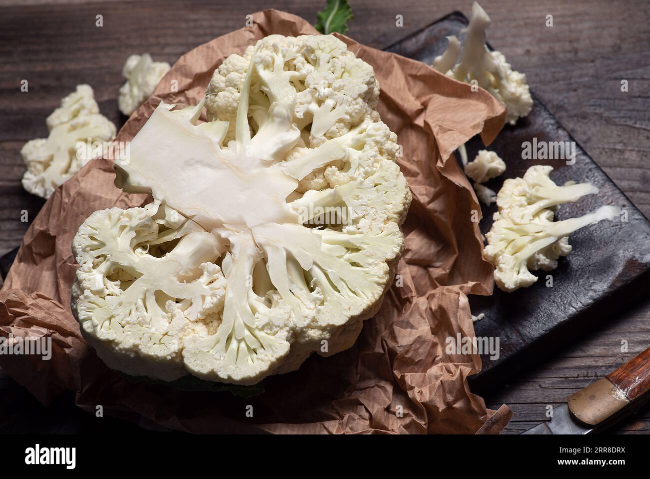 Frischer Bio-Blumenkohl auf Backpapier und Holzuntergrund Stockfoto