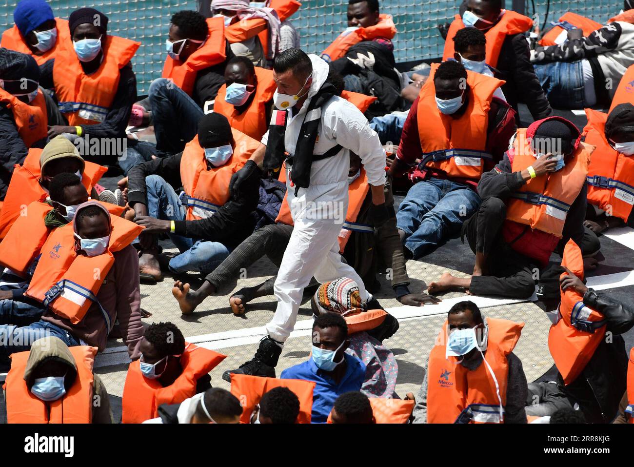 210512 -- SENGLEA, 12. Mai 2021 -- Ein Internierungsbeamter geht an Migranten vorbei, die bei ihrer Ankunft in Senglea, südlich von Malta, am 11. Mai 2021 Gesichtsmasken tragen. Eine Gruppe von rund 70 Migranten wurde nach Malta gebracht, nachdem sie im Süden der Insel am Montagabend nach einem Notruf gerettet worden waren, sagte ein Sprecher des Ministeriums für Inneres, nationale Sicherheit und Strafverfolgung am Dienstag. Foto von /Xinhua MALTA-SENGLEA-GERETTETE MIGRANTEN-ANKUNFT JonathanxBorg PUBLICATIONxNOTxINxCHN Stockfoto