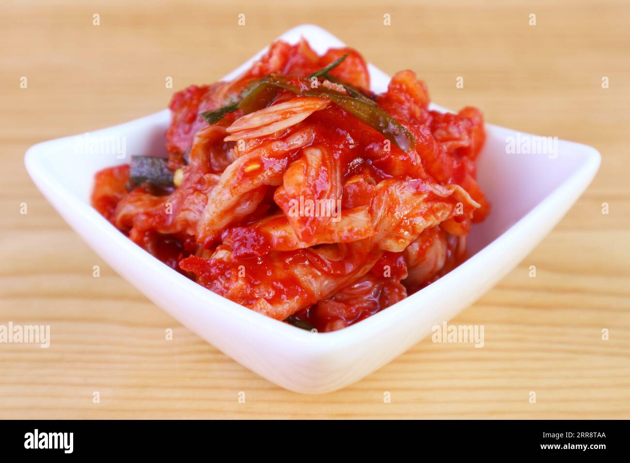 Nahaufnahme von Kimchi, einem ikonischen koreanischen Gericht in White Bowl auf Holzhintergrund Stockfoto
