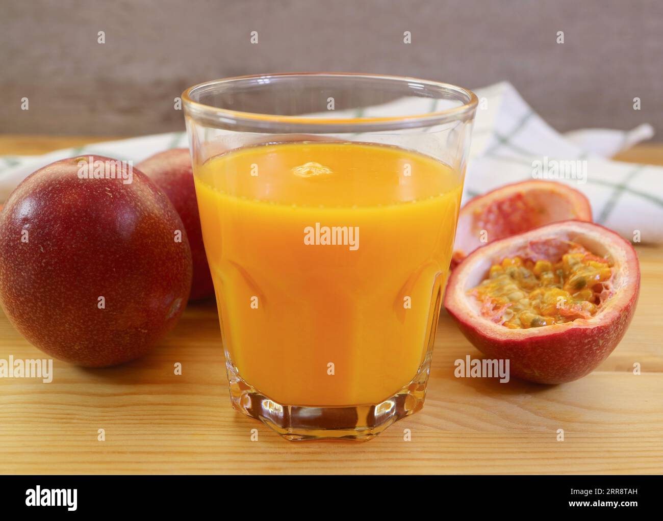 Ein Glas köstlicher frischer Passionsfruchtsaft mit einem Haufen voller Früchte im Hintergrund Stockfoto
