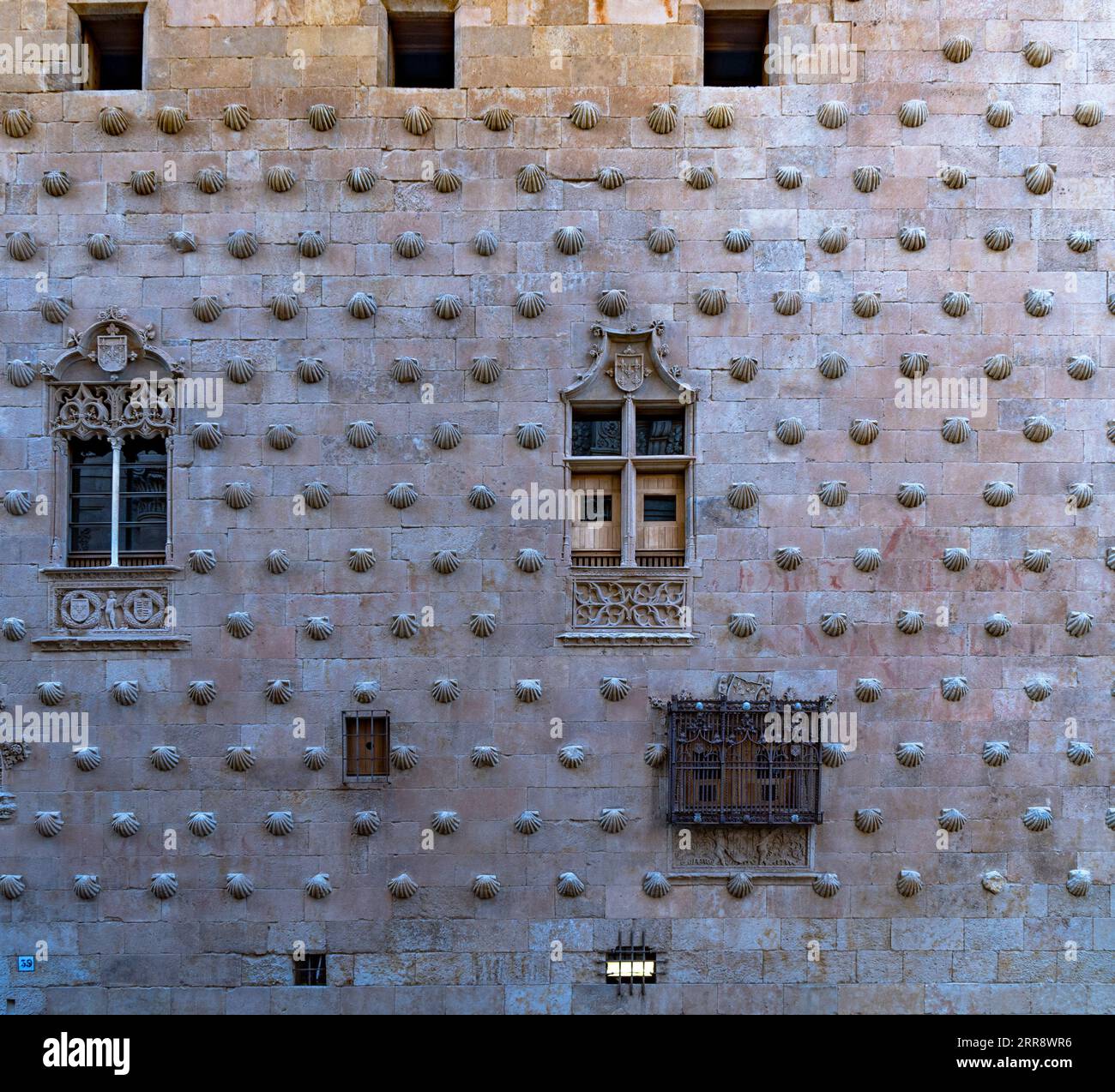 Fassade von La Casa de las Conchas mit schmiedeeisernen Fenstern, Zierleisten mit religiösen Motiven in Basreliefs und Felsenmuscheln in Salamanca in Spanien. Stockfoto